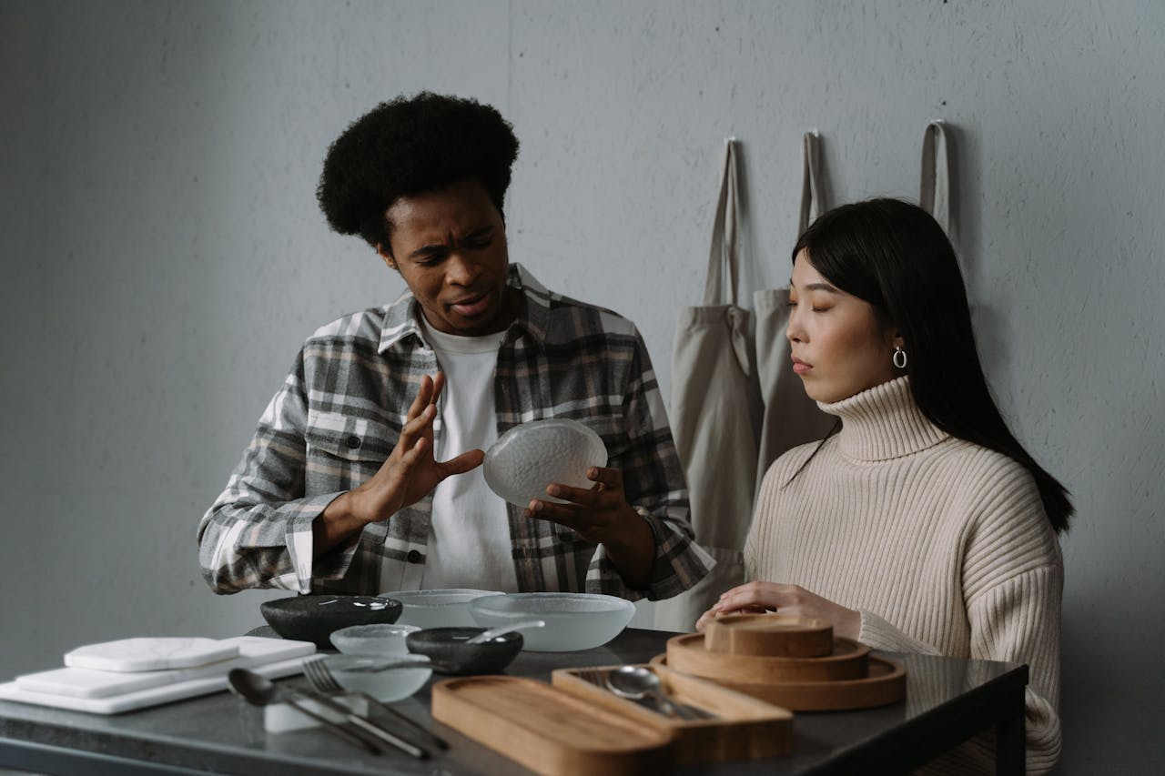 Home An African American man and Asian woman discussing modern tableware options in a stylish setting.